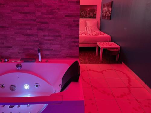 une salle de bain avec baignoire et une chambre avec un lit dans l'établissement SPA Enzo Appartement avec Jacuzzi Privatif, à Lyon