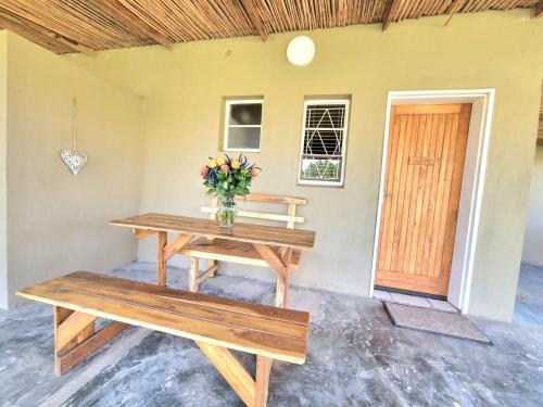 a table and benches in a room with a door at Kwetu Guest Farm in Swellendam