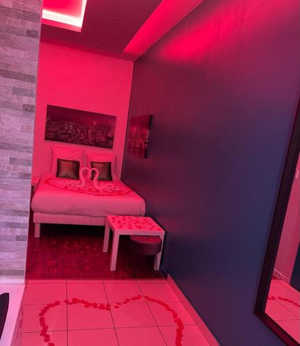 Cette chambre rose comprend un lit et une table. dans l'établissement SPA Enzo Appartement avec Jacuzzi Privatif, à Lyon