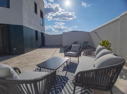 a patio with chairs and tables on a building at OIKOS APARTAMENTOS TURÍSTICOS in Monesterio