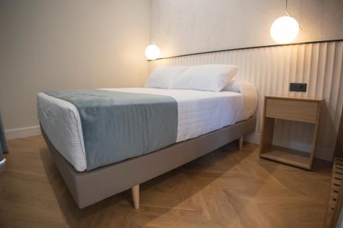 a bed in a room with two lights on at OIKOS APARTAMENTOS TURÍSTICOS in Monesterio