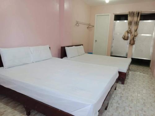 uma grande cama branca num quarto com uma janela em Cebu Leisure Lodge em Cebu