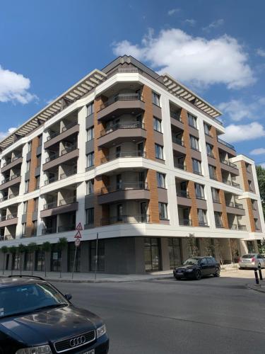 un gran edificio de apartamentos con coches aparcados frente a él en Amarant Aparts, en Sofía