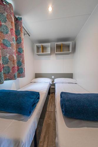 a room with three beds with blue pillows at Albatross Mobile Homes on Camping Playa Brava in Pals