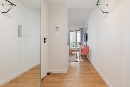 a hallway with white walls and a table and chairs at Apartments Mazowiecka Pobierowo by Noclegi Renters in Pobierowo