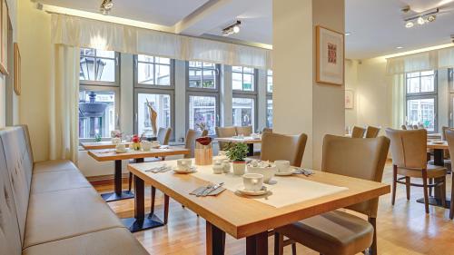 - une salle à manger avec des tables, des chaises et des fenêtres dans l'établissement Mühlhäuser Hof- Stadtmauer- Rabe, à Mühlhausen