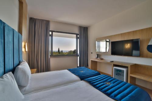 Habitación de hotel con cama y TV en Nashira City Resort Hotel, en Antalya