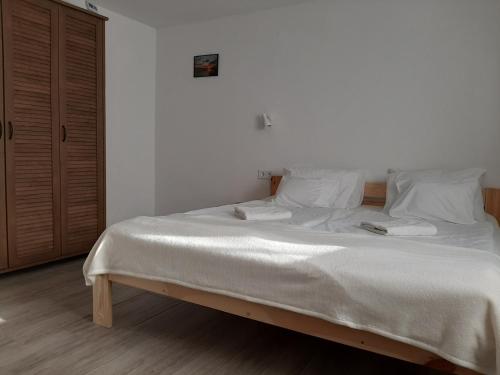 1 dormitorio con 1 cama grande con sábanas y almohadas blancas en Hódvár Apartman, en Tiszafüred