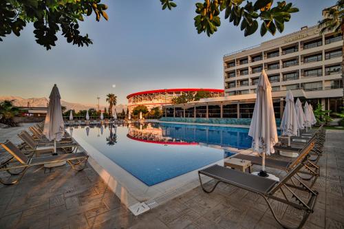 Nashira City Resort Hotel في أنطاليا: مسبح مع كراسي ومظلات أمام المبنى