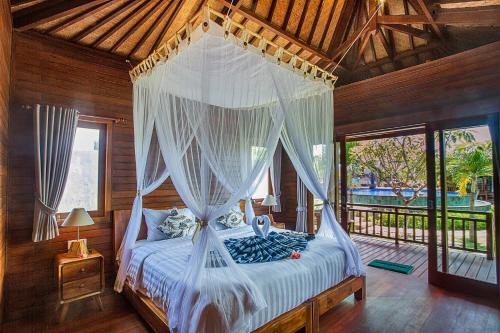 a bedroom with a canopy bed with white curtains at Pondooks Joglo in Nusa Lembongan