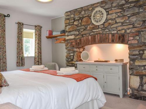 a bedroom with a large bed and a stone wall at Ysgubor Blaenparc Barn - Uk41030 in Mydroilin