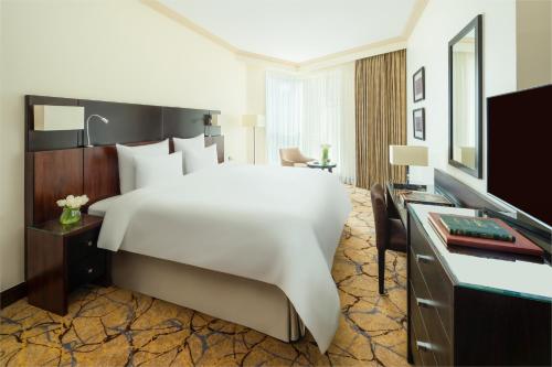 um quarto de hotel com uma grande cama branca e uma secretária em Movenpick Makkah Hajar Tower em Meca