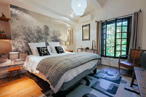 une chambre avec un grand lit et une grande fenêtre dans l'établissement Le Moulin de Boursac, à Vence