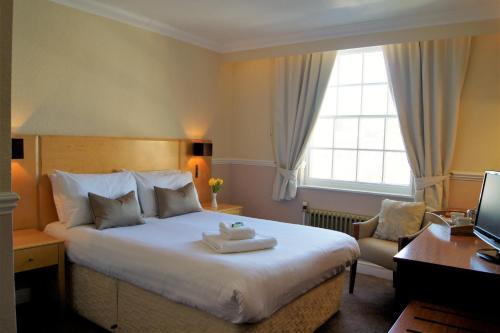 a hotel room with a bed and a desk and a window at The Bulkeley Hotel in Beaumaris