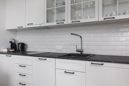 a kitchen with white cabinets and a sink at Apartments Mazowiecka Pobierowo by Noclegi Renters in Pobierowo