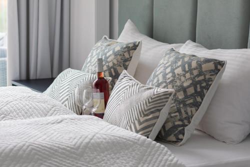 a bunch of pillows and a bottle of wine on a bed at Apartments Mazowiecka Pobierowo by Noclegi Renters in Pobierowo