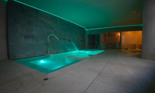 een grote badkamer met een bad met groene verlichting bij OIKOS APARTAMENTOS TURÍSTICOS in Monesterio
