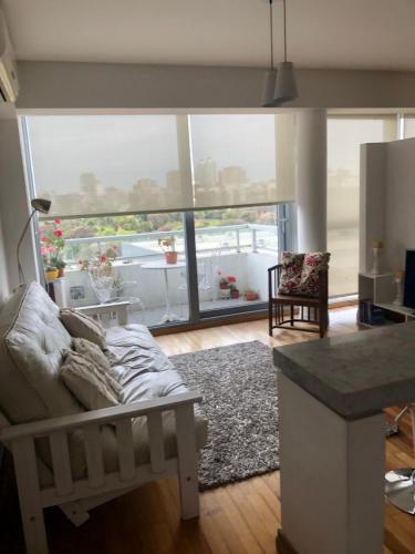 ein Wohnzimmer mit einem Sofa und einem großen Fenster in der Unterkunft Apartamento Av kennedy y Cerviño a metros embajada EEUU in Buenos Aires