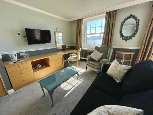 a living room with a couch and a tv at The Bulkeley Hotel in Beaumaris
