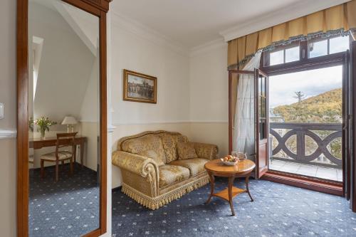 a living room with a couch and a table and a window at Spa Hotel Villa Ritter in Karlovy Vary