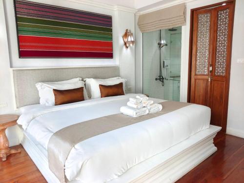 a bedroom with a large white bed with towels on it at Lanna Oriental Hotel in Chiang Mai