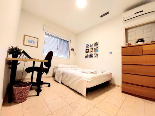 a bedroom with a bed and a desk with a computer at Happy Vacation House in Zikhron Ya‘aqov