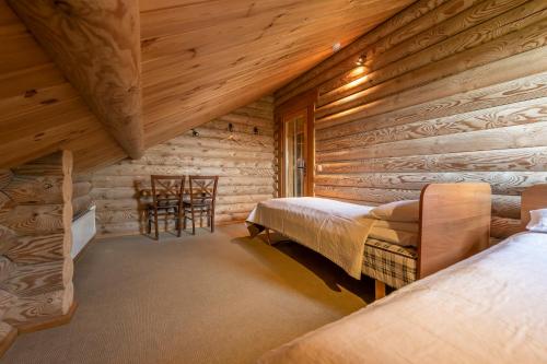 Dormitorio en cabaña de madera con 2 camas y una silla en Alauso Slenis, en Sudeikiai
