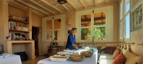 a woman standing in a kitchen with a table at Maison d'Hôtes Irocha in Tisselday
