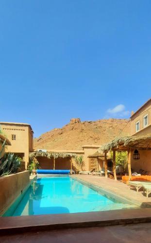 a swimming pool in a resort with a mountain in the background at Maison d'Hôtes Irocha in Tisselday