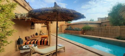 a bed and an umbrella next to a pool at Maison d'Hôtes Irocha in Tisselday