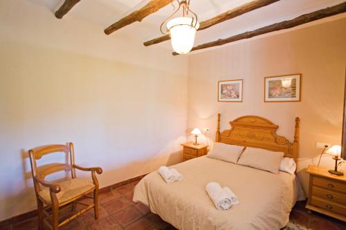 a bedroom with a large bed and a chair at Villa La Margarita Rocabella in El Chorro