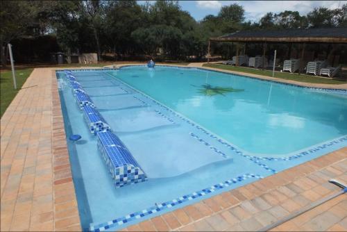 een groot zwembad met blauw water bij The Aces - NUDE - SunEden Family Naturist Resort in Pretoria