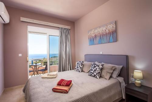 a bedroom with a bed with a view of the ocean at Kalypso Sea View Villa in Koskinou