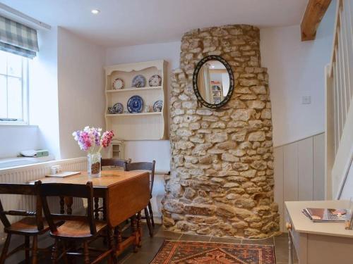 a dining room with a table and a stone wall at Fern Dale Cottage in Stockland
