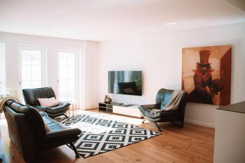 a living room with two chairs and a flat screen tv at Just Like Home - Casinhas da Vila T2 em Caminha in Caminha