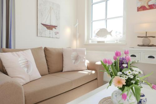 a living room with a couch and a vase of flowers at Haus Meeresblick FeWo Strandperle in Baabe