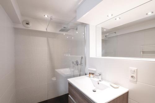 ein weißes Badezimmer mit einem Waschbecken und einem Spiegel in der Unterkunft Appartement Chesery in Chamonix-Mont-Blanc