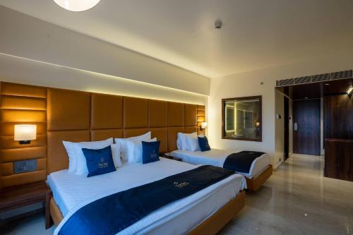a hotel room with two beds with blue pillows at Mastiff Grand The Sia Palace Suites & Banquets, Khopoli, Near Imagica in Khopoli