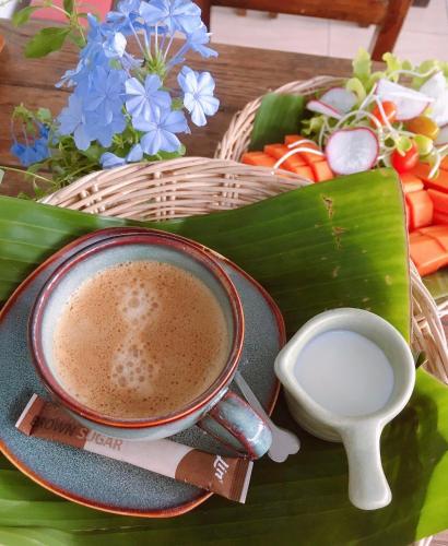 a cup of coffee on a plate on a table with vegetables at Wayside Guesthouse in Chiang Mai
