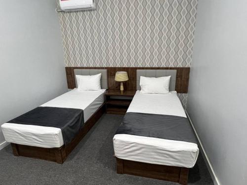 two twin beds in a small room at TASHRIF HOTEL in Qarshi