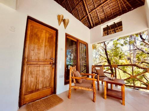 a room with a door and a chair and a table at Helwas Zanzibar Beach Hotel in Bwejuu