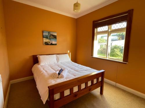 a bedroom with a bed with orange walls and a window at NO PARTY ALLOWED, Peaceful, Spacious, central Petone, free unlimited Fibre Wi-Fi & free parking in Lower Hutt