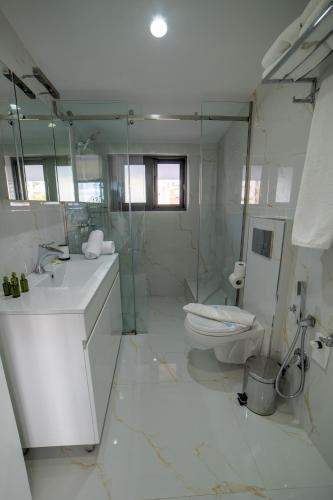 a white bathroom with a toilet and a sink at Epirus Hotel in Sarandë