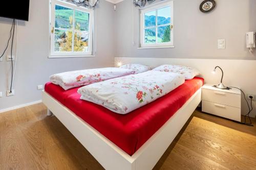 a bedroom with a bed with a red blanket and two windows at Alpen Living - 1 Stock Ganz in Cadipietra
