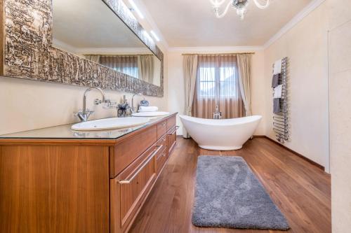 ein Badezimmer mit zwei Waschbecken, einer Badewanne und einem Spiegel in der Unterkunft Alpen Living - 1 Stock Ganz in Steinhaus