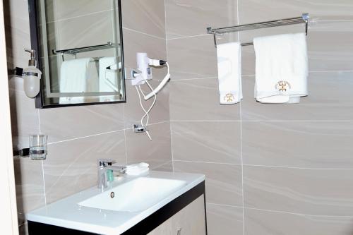 a bathroom with a sink and a mirror and towels at Hôtel Printemps Mont Korhogo in Korhogo