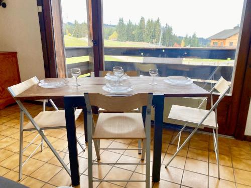 una mesa con sillas, platos y vasos. en Grand Studio aux pieds des pistes sans vis à vis, en Les Gets