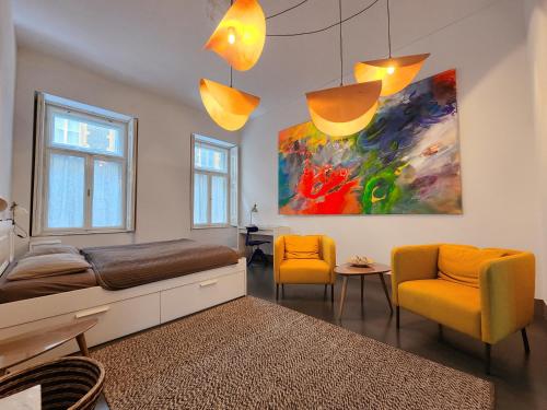 a bedroom with a bed and two chairs and a painting at Stylish holiday Art apartment - wifi & great location in Budapest
