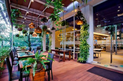 a restaurant with tables and chairs and plants at Deka Hotel Surabaya HR Muhammad in Surabaya