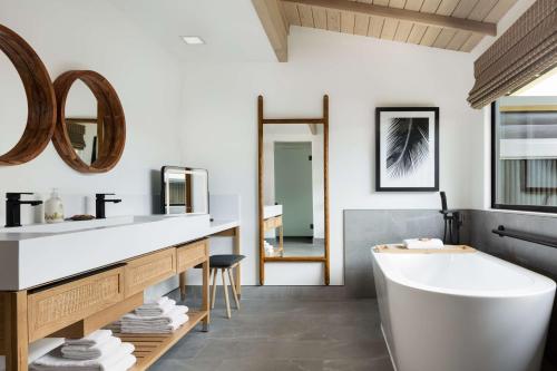 a bathroom with a tub and a sink and mirror at Hana-Maui Resort, a Destination by Hyatt Residence in Hana
